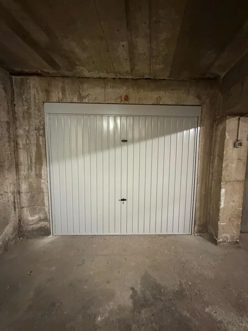 Porte de garage basculante blanche posée dans un box