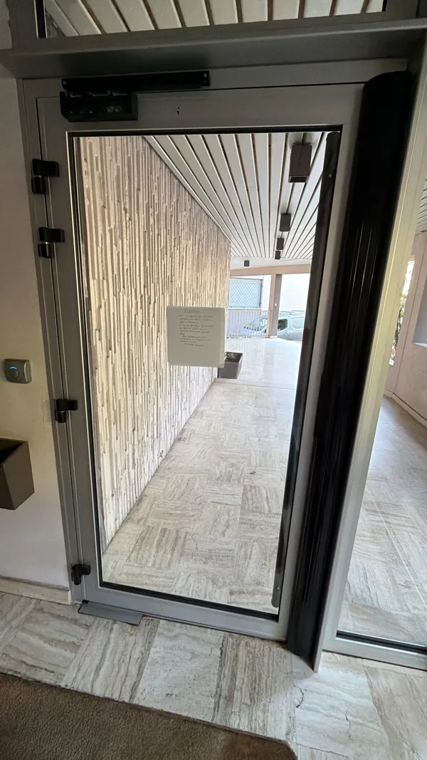 Porte vitrée aluminium avec ferme-porte installée par KB Services